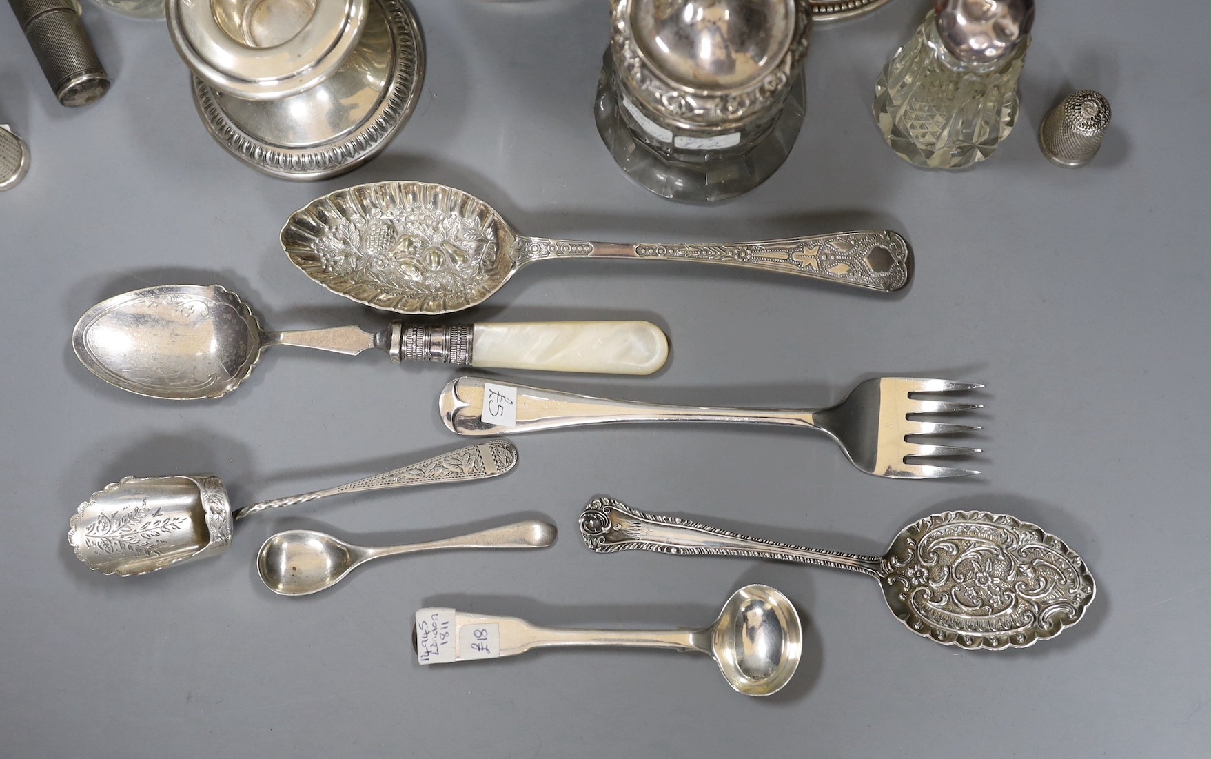 Small silver items including 800 standard dwarf candlestick, a George V silver mounted pin cushion, a silver mounted glass atomiser and two toilet jars, a sterling lighter, two silver thimbles, four items of silver flatw